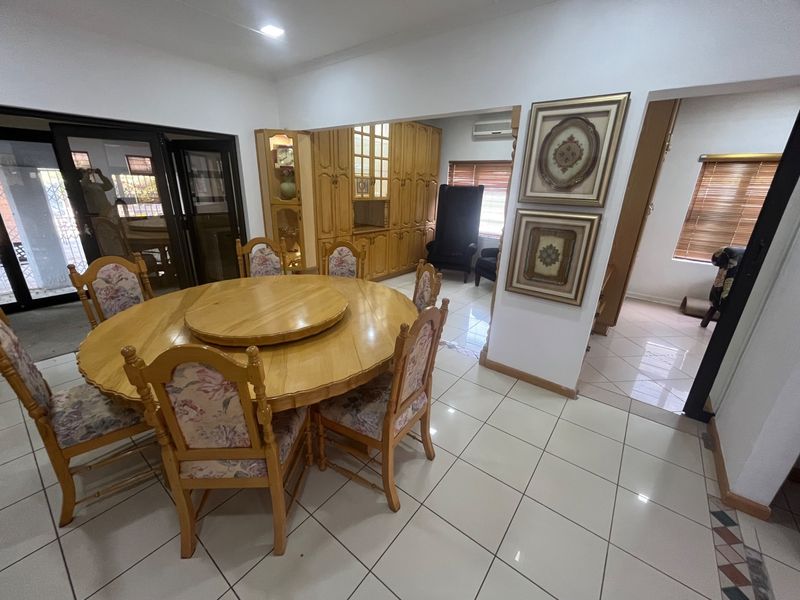 Dining area featuring tiled flooring, built-in wooden cabinetry, and access to an adjacent space through sliding glass doors.