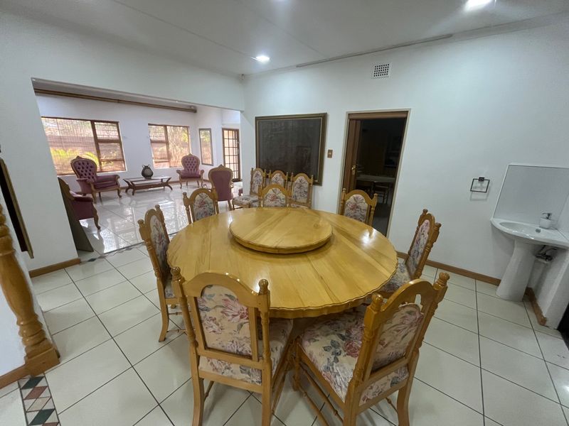 Spacious dining area featuring tiled flooring, a pedestal sink, and large windows, providing an open-plan layout connected to the adjacent living space.