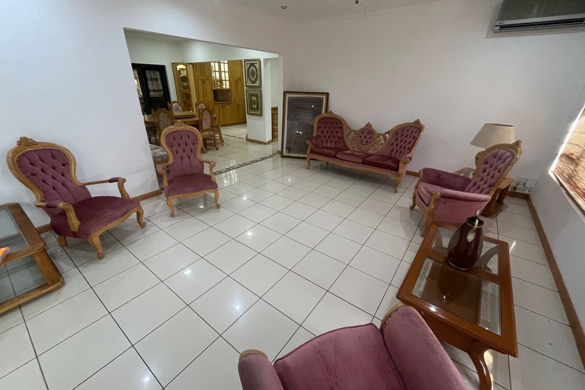 Spacious living area featuring neutral ceramic floor tiles, track lighting, and a wall-mounted split-system air conditioner, with an open-plan flow to the dining area.