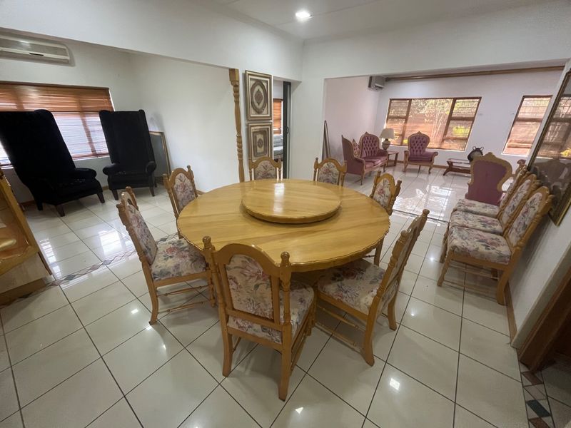 Spacious open-plan living and dining area featuring neutral tiled flooring, recessed lighting, and large windows with venetian blinds.