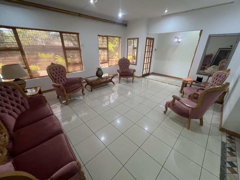 Spacious living room featuring large windows with timber frames, neutral tiled flooring, and recessed downlighting, offering a bright and open layout.
