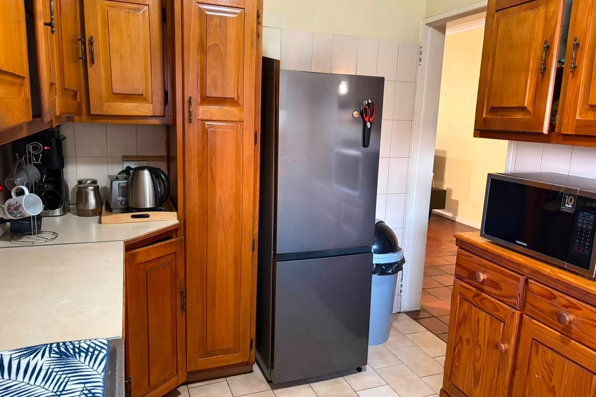 A functional kitchen featuring traditional wooden cabinetry, tiled backsplash, and tiled flooring, offering a classic aesthetic with ample storage space.