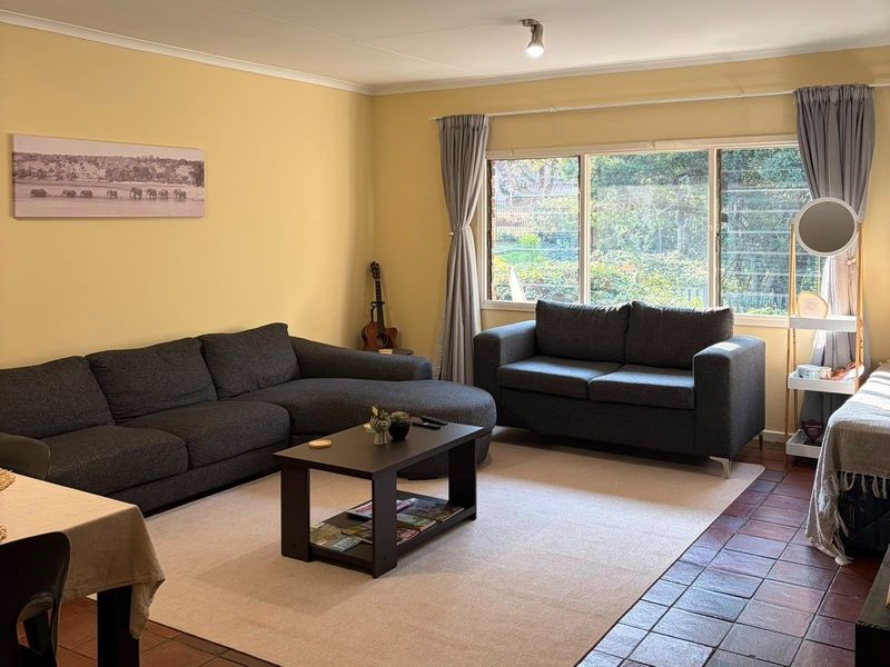 A comfortable living room featuring large windows that provide natural light and views of the garden, complemented by durable tiled flooring.