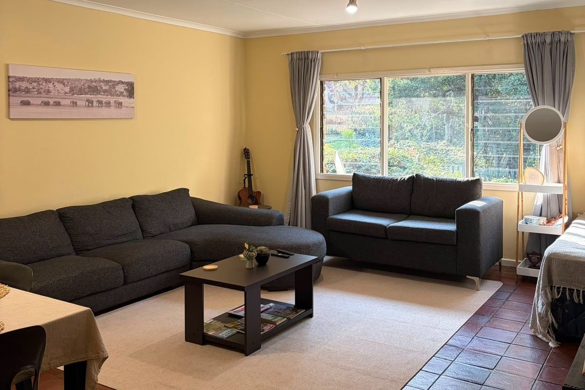 A comfortable living room featuring large windows that provide natural light and views of the garden, complemented by durable tiled flooring.