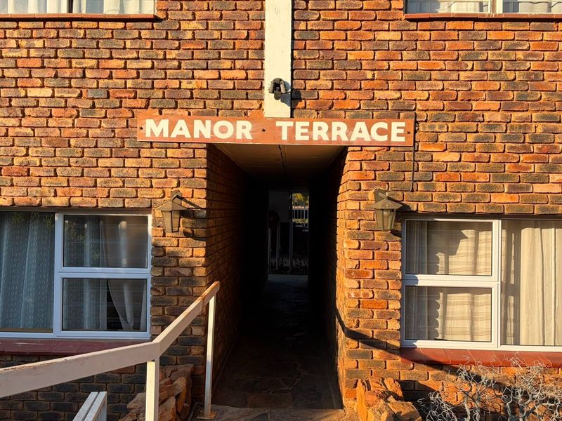 Front entrance view of Manor Terrace apartment complex featuring exposed brick facade and exterior lighting.