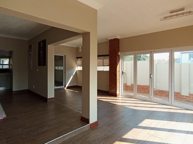 Spacious open-plan living area featuring tiled floors, an exposed brick feature pillar, and large stacking glass doors leading to the exterior.