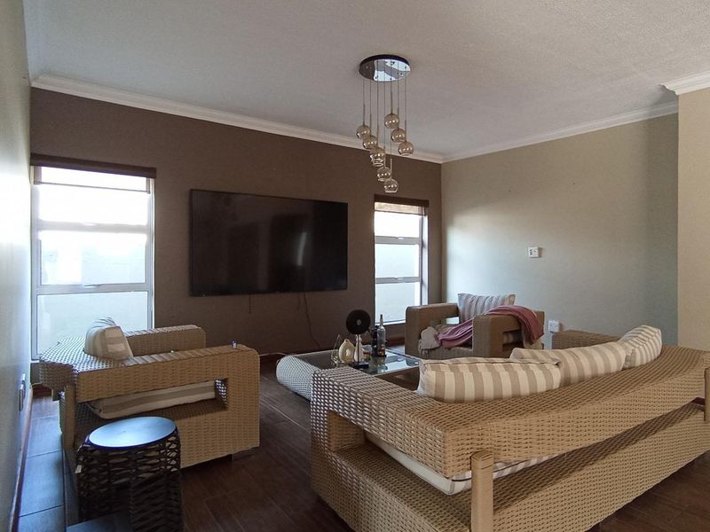 A comfortable living room featuring tiled flooring, cove cornicing, and modern pendant lighting, providing a functional space for relaxation.