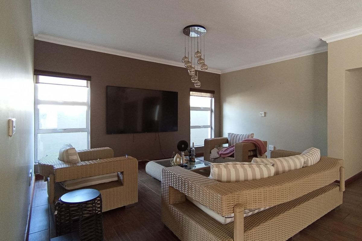 A comfortable living room featuring tiled flooring, cove cornicing, and modern pendant lighting, providing a functional space for relaxation.