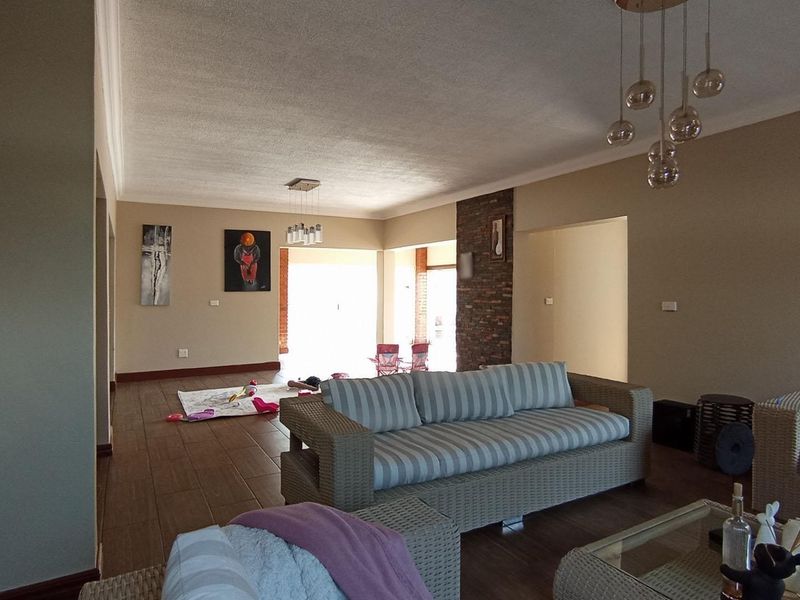 Spacious living area featuring tiled flooring, an exposed brick feature wall, and modern pendant lighting, offering a versatile layout for comfortable family living.