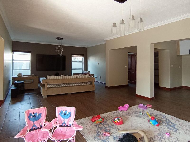 Spacious open-plan living area featuring a stone feature wall, tiled flooring, and a connected kitchen with built-in cabinetry and island.