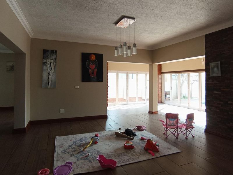 Spacious open-plan living area featuring tiled floors, a stone accent wall, and large sliding glass doors providing ample natural light and garden access.
