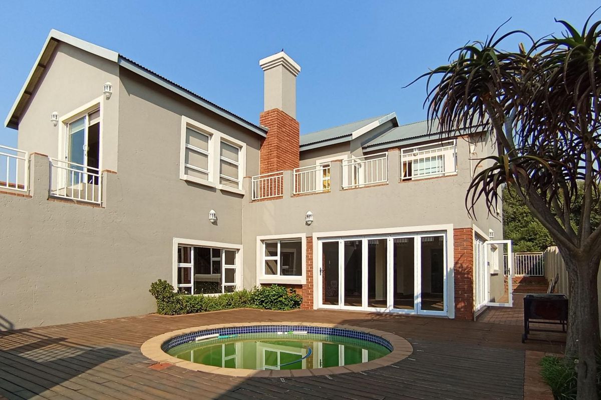Rear exterior view featuring a circular swimming pool, timber decking, brick chimney, and balcony access from the upper level.