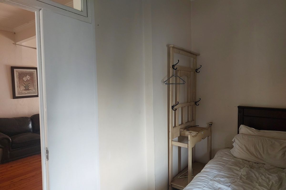 A bedroom interior featuring a doorway with a transom window, providing a view into the adjacent living area.