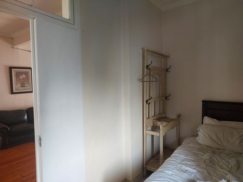 A bedroom interior featuring a doorway with a transom window, providing a view into the adjacent living area.