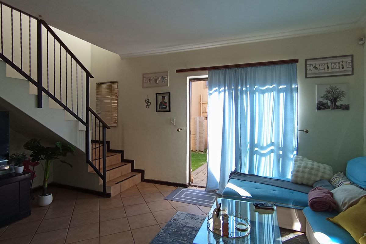 Living room featuring tiled flooring, a staircase with a metal balustrade, and direct access to the rear garden through a sliding door.