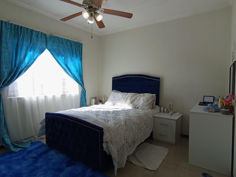 A functional bedroom featuring tiled flooring and a ceiling fan, providing a comfortable and well-lit sleeping space.