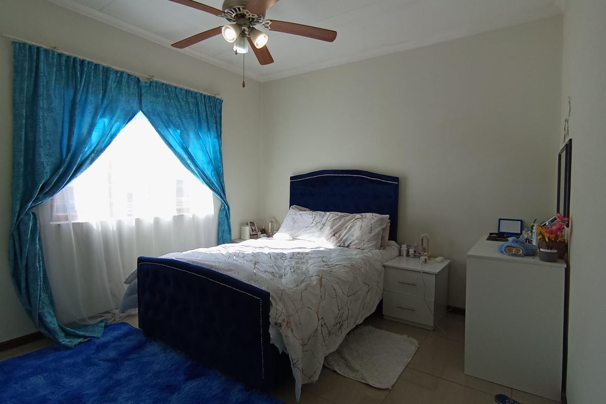 A functional bedroom featuring tiled flooring and a ceiling fan, providing a comfortable and well-lit sleeping space.