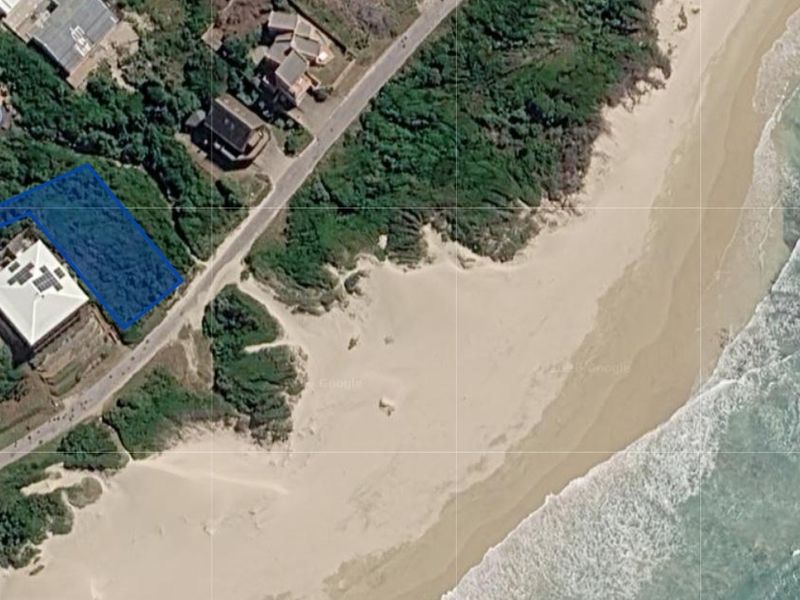 Aerial view of a vacant residential plot situated in a coastal location near the beach and dunes.
