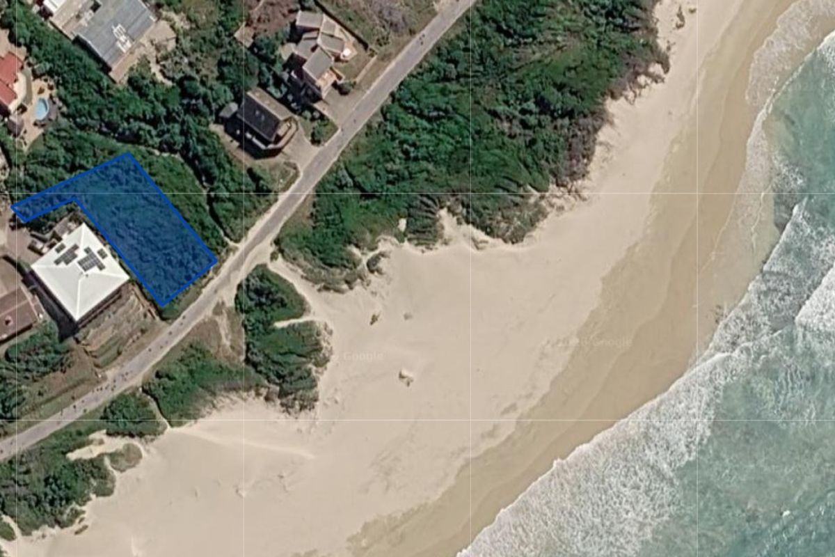 Aerial view of a vacant residential plot situated in a coastal location near the beach and dunes.