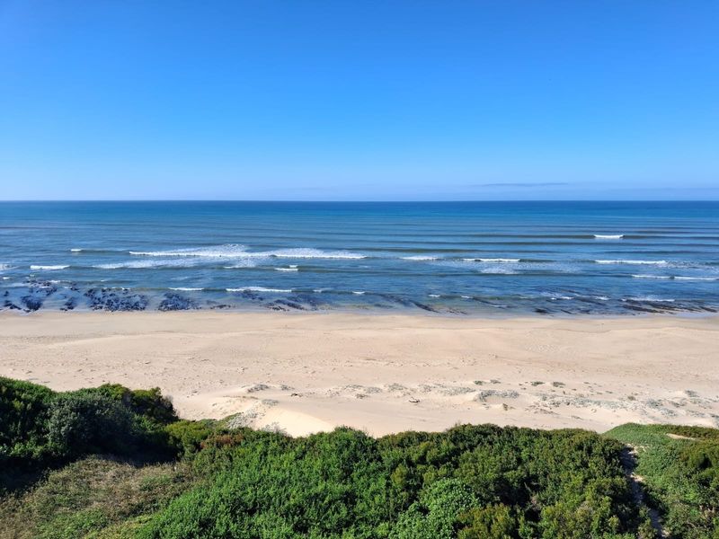 A scenic, elevated view of the sandy beach and ocean, showcasing the natural coastal landscape of the property.