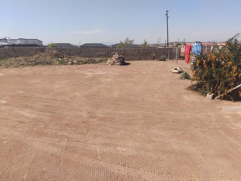 A vacant residential plot featuring a perimeter masonry wall and level ground, offering a blank canvas for future landscaping or development.