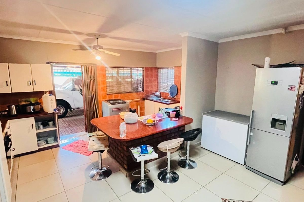 A functional kitchen featuring a central island, tiled flooring, and built-in cabinetry, with direct access to the exterior driveway area.