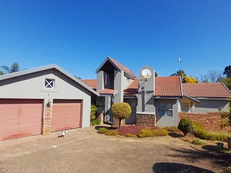 Front elevation of a residential house featuring a double garage, tiled roof, and paved driveway with established garden landscaping.