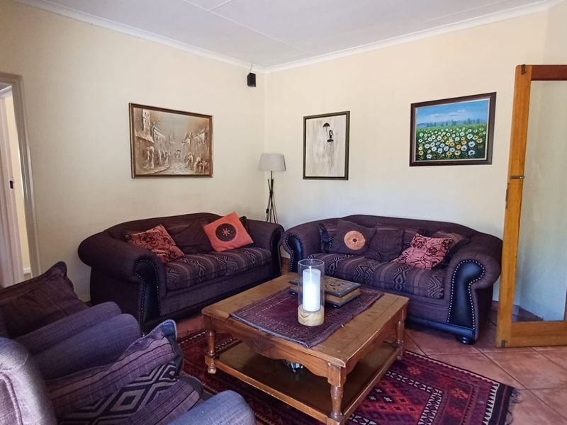 A comfortable living room featuring tiled flooring, coved ceilings, and a timber-framed glass door leading to an adjacent space.