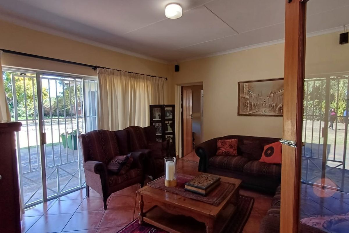 A comfortable living room featuring tiled flooring, coved ceilings, and a large sliding glass door providing direct access to the garden.