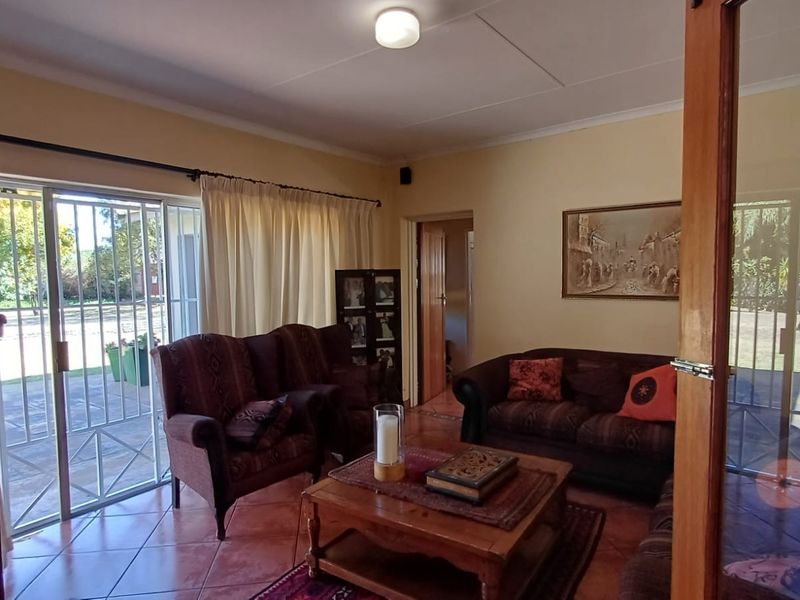 A comfortable living room featuring tiled flooring, coved ceilings, and a large sliding glass door providing direct access to the garden.