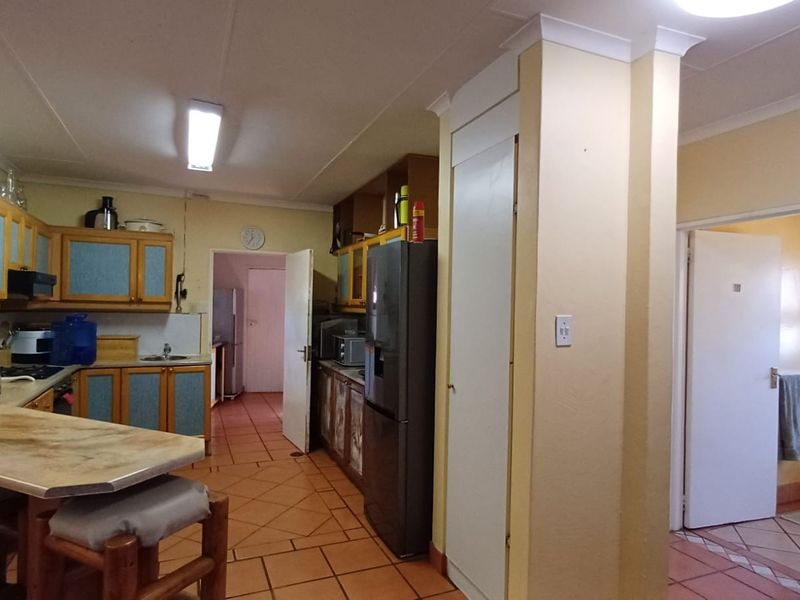 A functional kitchen featuring dated cabinetry, tiled flooring, and a breakfast counter, offering potential for a modern renovation.