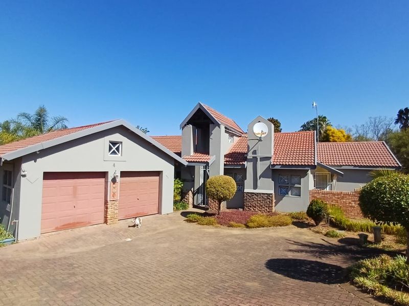 Front elevation of a residential house featuring a double garage, tiled roof, and a paved driveway with established garden landscaping.