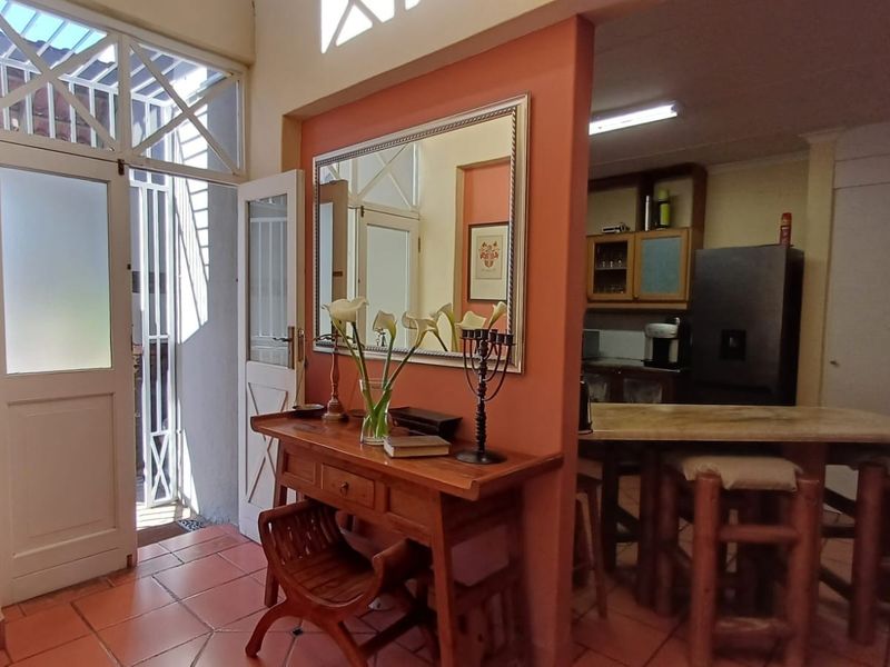 Open plan living area featuring terracotta tiled flooring, a breakfast counter, and direct access to an exterior entrance with a security gate.