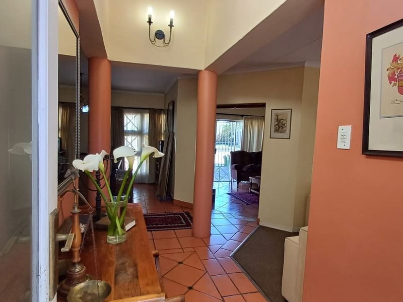 A spacious entrance hallway featuring terracotta floor tiles and structural columns, providing a central access point to the living areas of the home.