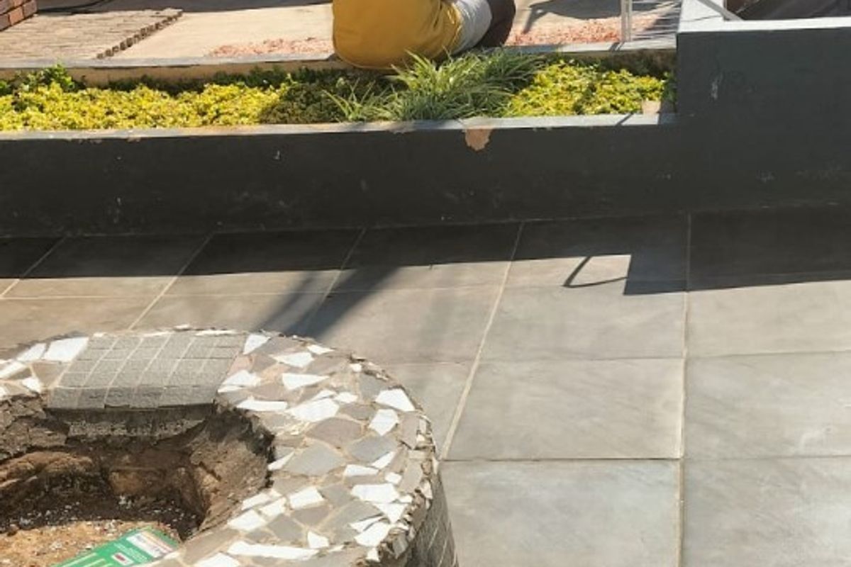 Outdoor patio area featuring tiled flooring, a brick boundary wall, a raised garden bed, and a circular fire pit.