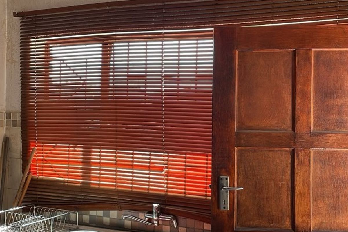 Kitchen area featuring a stainless steel sink, built-in cabinetry, and timber door, showing significant signs of ceiling water damage and wear.