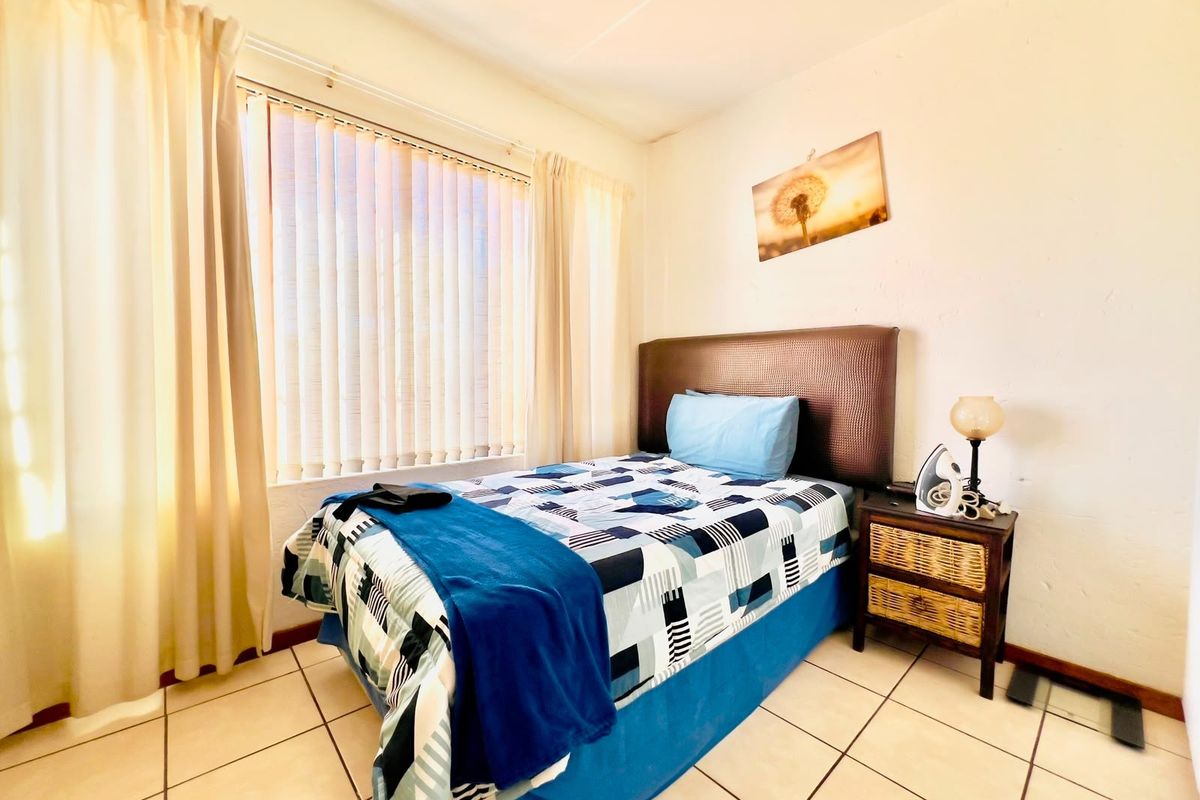A functional bedroom featuring tiled flooring and vertical blinds, providing a neutral space ready for personalization.