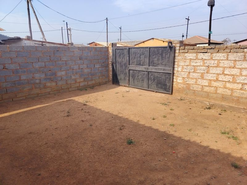 A private rear yard area enclosed by concrete block boundary walls and featuring a metal access gate.