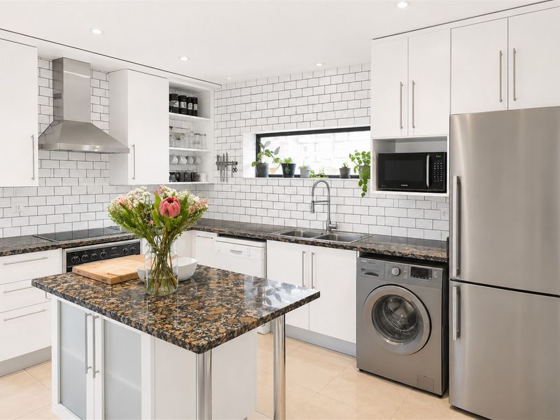 Modern kitchen featuring white cabinetry, granite countertops, subway tile backsplash, and integrated stainless steel appliances, including a central island and recessed lighting.