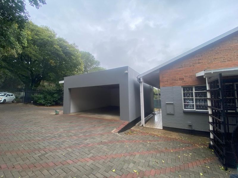 A view of a detached garage structure with a paved driveway and adjacent brick house exterior.