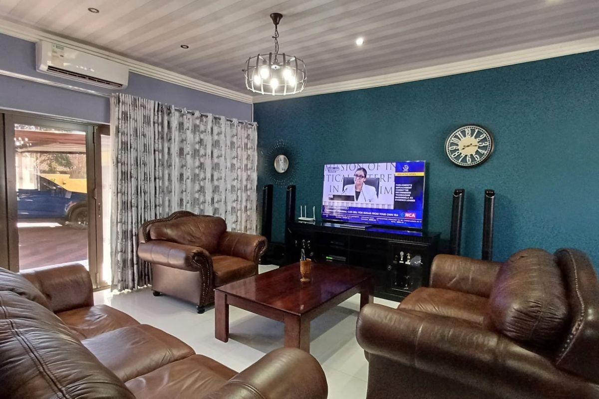 A comfortable living room featuring tiled flooring, a split-system air conditioner, and large sliding glass doors providing access to the exterior.