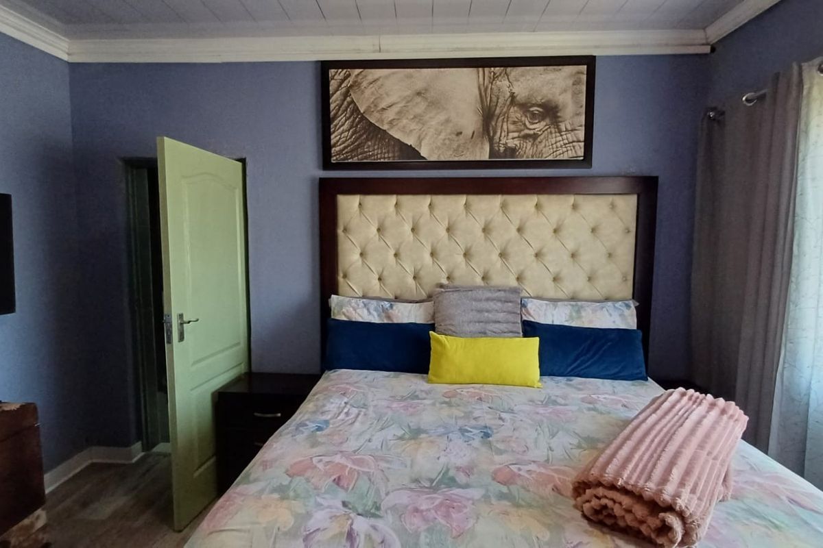 A bedroom featuring blue walls, crown molding, and a tufted headboard, providing a comfortable and functional sleeping space.