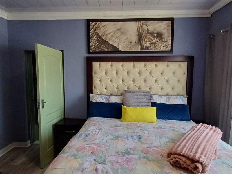A bedroom featuring blue walls, crown molding, and a tufted headboard, providing a comfortable and functional sleeping space.