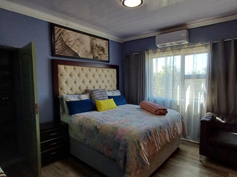 A cozy bedroom featuring laminate flooring, ceiling paneling, and a wall-mounted air conditioning unit, providing a comfortable and functional living space.