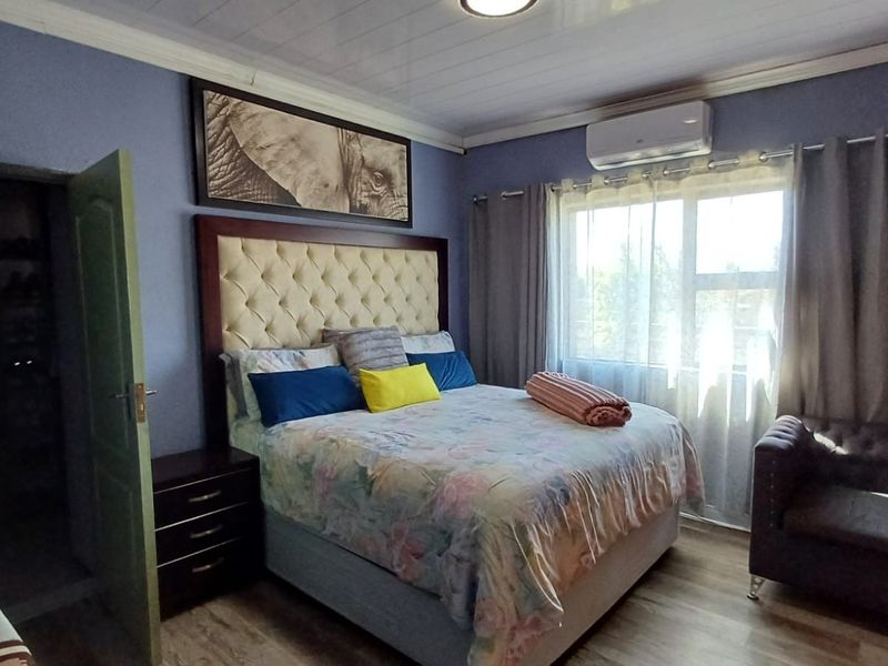A comfortable bedroom featuring laminate flooring, an air conditioning unit, and a built-in closet, offering a functional and well-maintained living space.