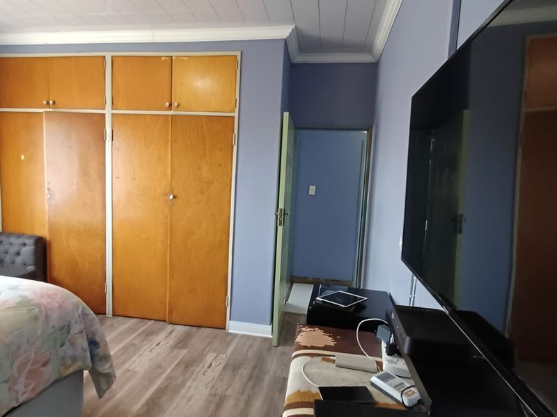 A bedroom featuring built-in wooden cupboards, laminate flooring, and a coved ceiling, providing a functional and neutral living space.