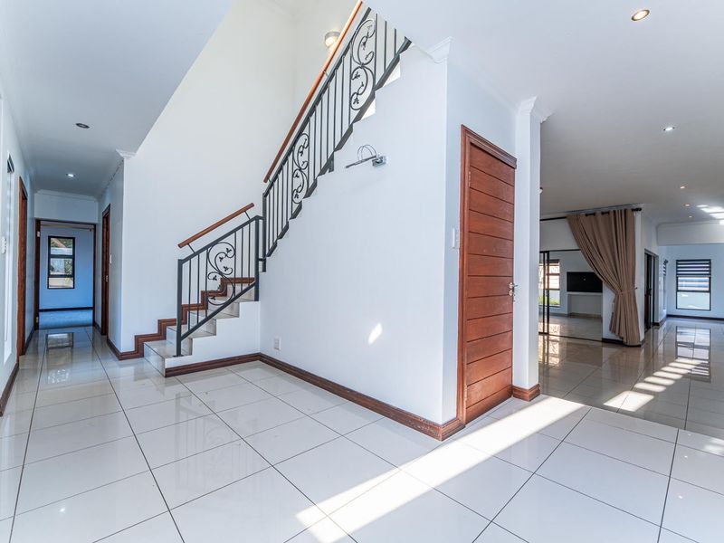 Spacious entrance hall featuring tiled flooring, a staircase with a decorative wrought iron balustrade, and access to adjacent living areas.