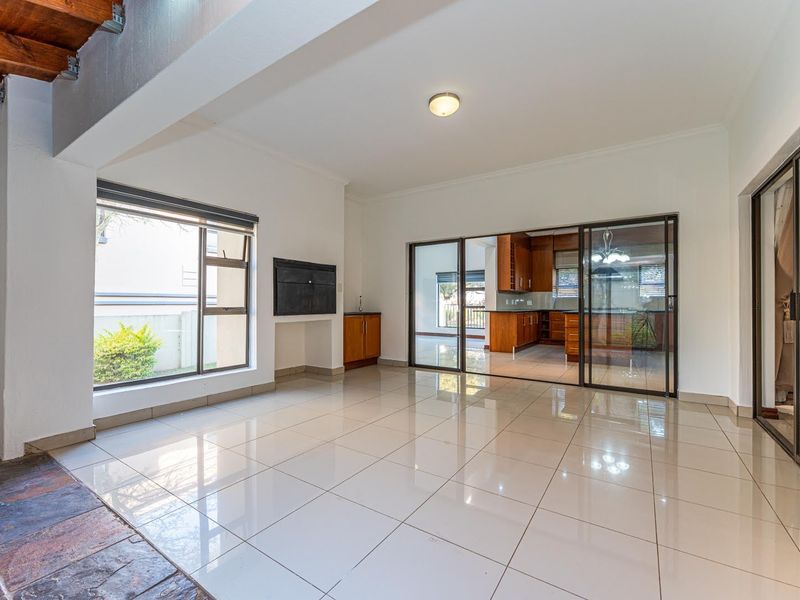 Spacious open-plan living area featuring polished tile flooring, a built-in fireplace, and large sliding glass doors providing seamless access to the kitchen and exterior.