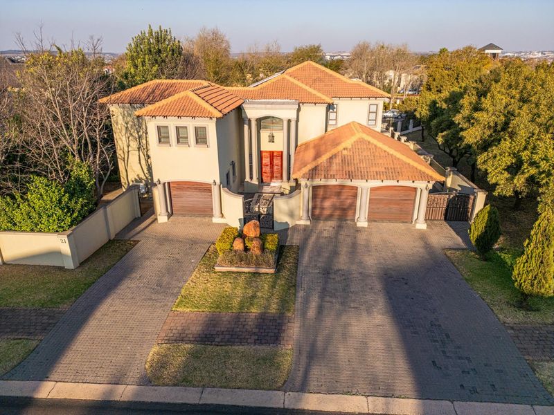 Aerial view of a substantial double-storey residence featuring a terracotta tile roof, triple garage, and extensive paved driveway.