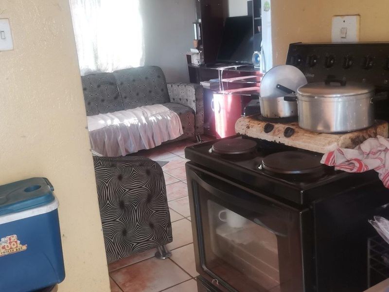 Open plan living and kitchen area featuring tiled flooring and a freestanding stove, requiring cosmetic updates to improve the overall aesthetic.